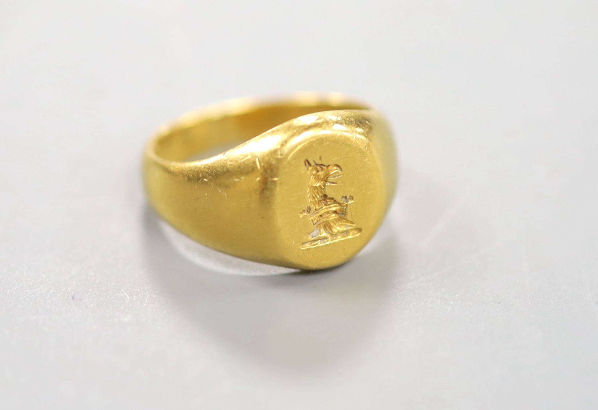 An early 20th century yellow metal(stamped 22) intaglio crested signet ring, size J, 8.6 grams.